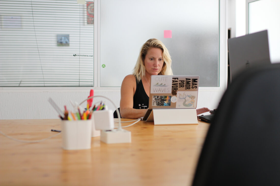 Chel Rogerson at her laptop in a large coworking space with lots of natural light in Fuerteventura